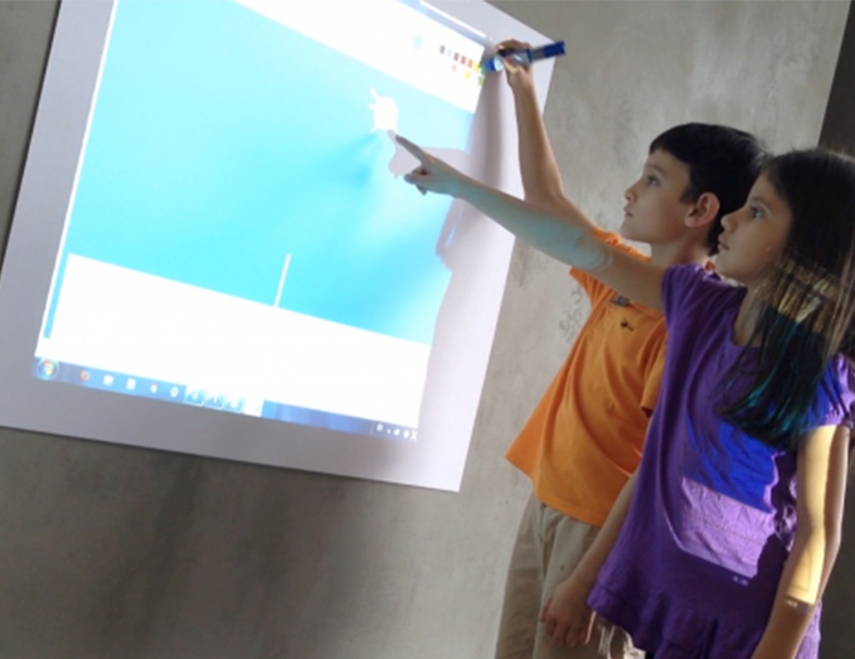 Un niño y una niña interactuando con una imagen proyectada en una pantalla.